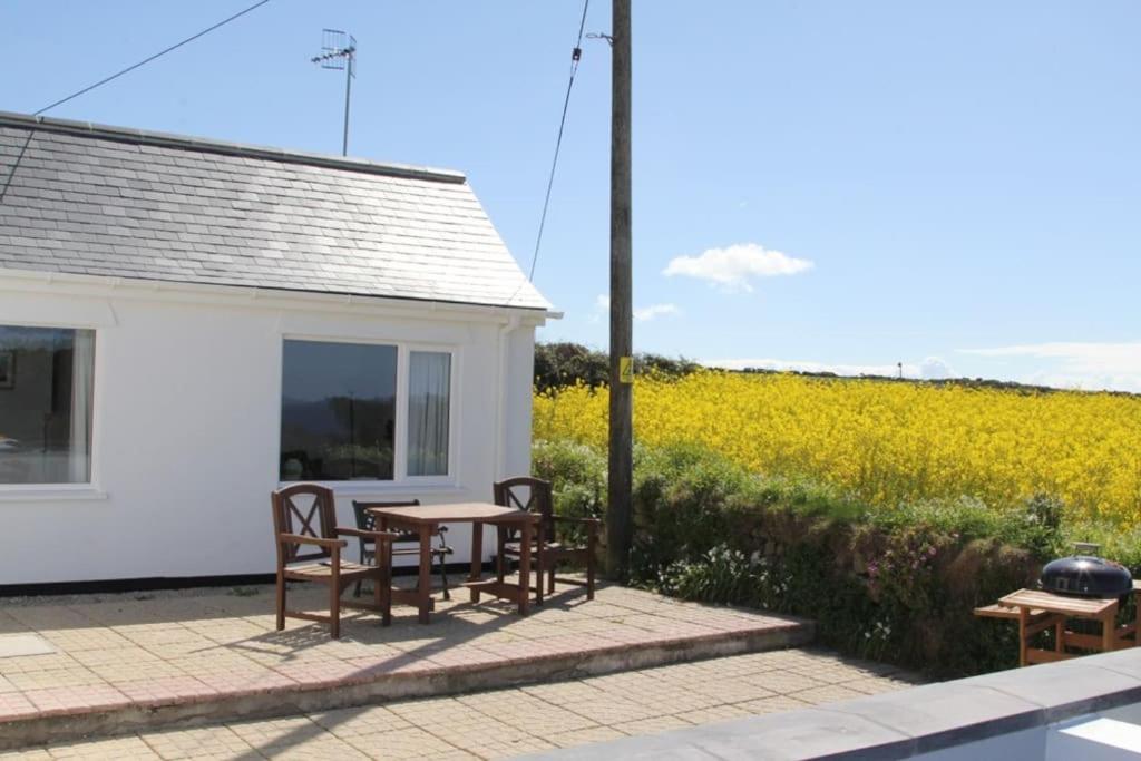 a patio with a table and chairs and a field of flowers at The Old Dairy, Land's End, Sennen in Sennen