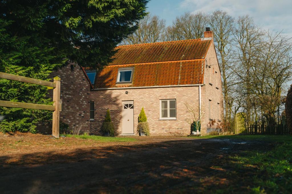 uma antiga casa de tijolos com um telhado laranja em De Dommelhoeve em Peer