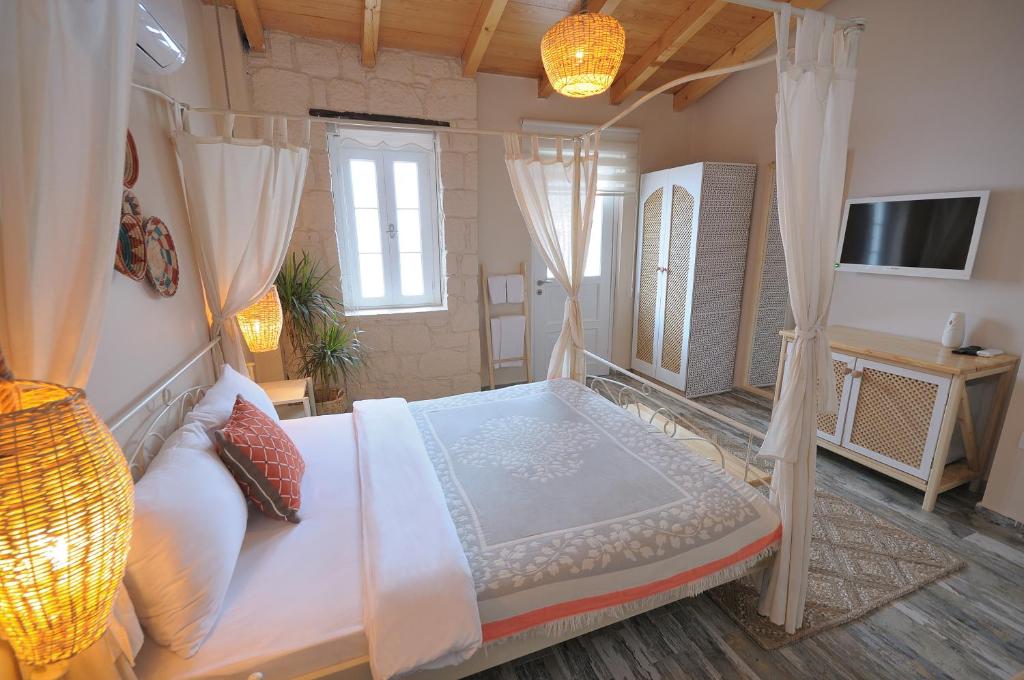 a bedroom with a canopy bed with curtains and a television at Hera Hotels Alaçatı in Cesme