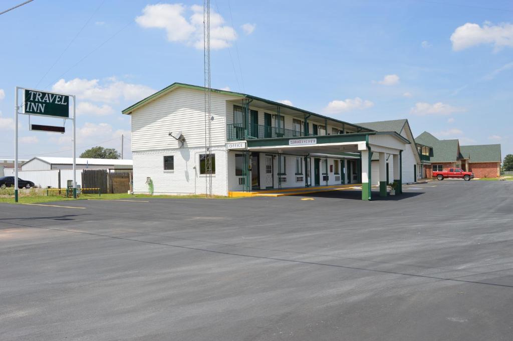 a white building with a parking lot in front of it at Travel Inn Weatherford in Weatherford