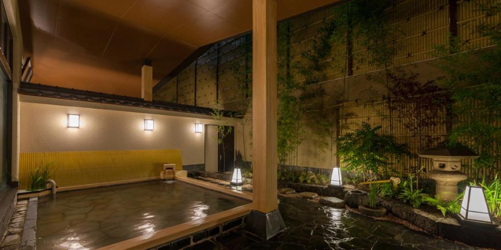 a large swimming pool in a building with a pond at Nishitetsu Resort Inn Beppu in Beppu