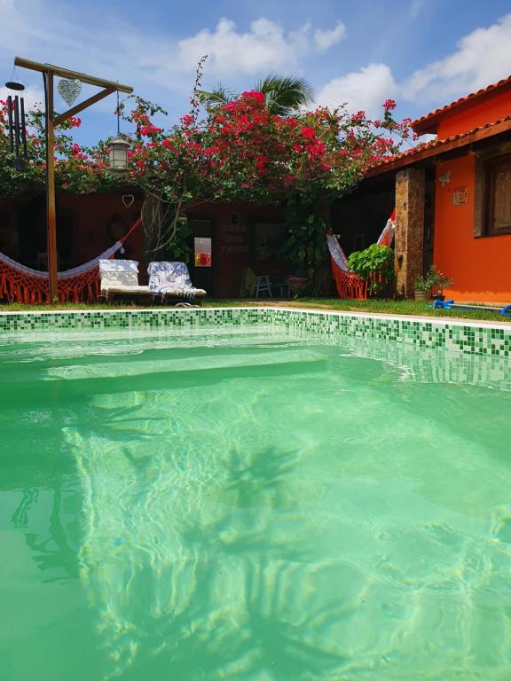 a swimming pool in front of a house with flowers at Casa Dos Patos in Flecheiras