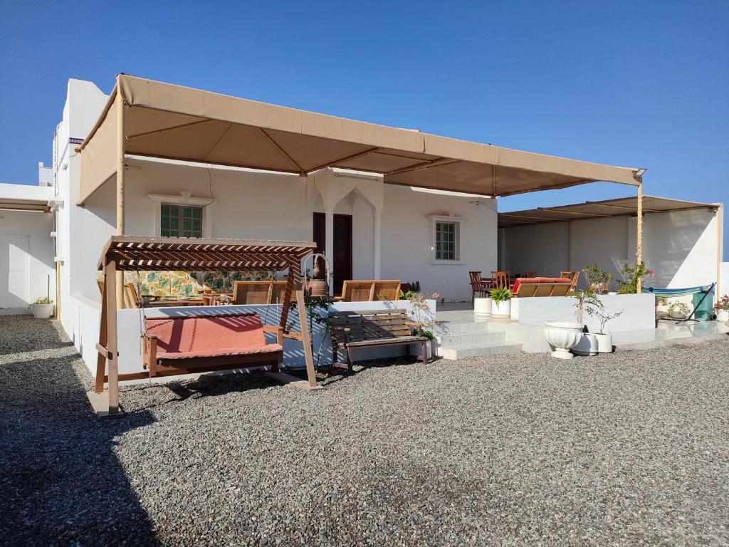 a patio with a large umbrella in front of a house at Ras Al Hadd Orchid in Al Ḩadd