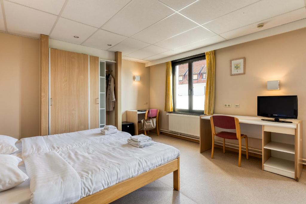 a hospital room with a bed and a desk and a television at Corsendonk Duinse Polders in Blankenberge