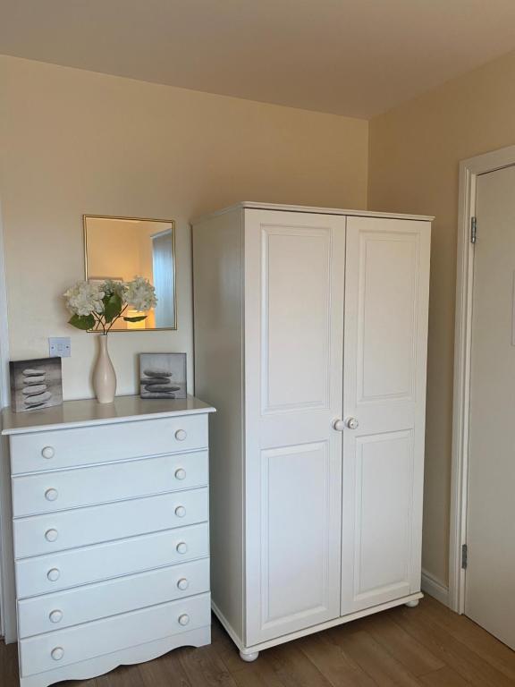 a bedroom with a white dresser and a white cabinet at Village Way Apartments in Kincasslagh