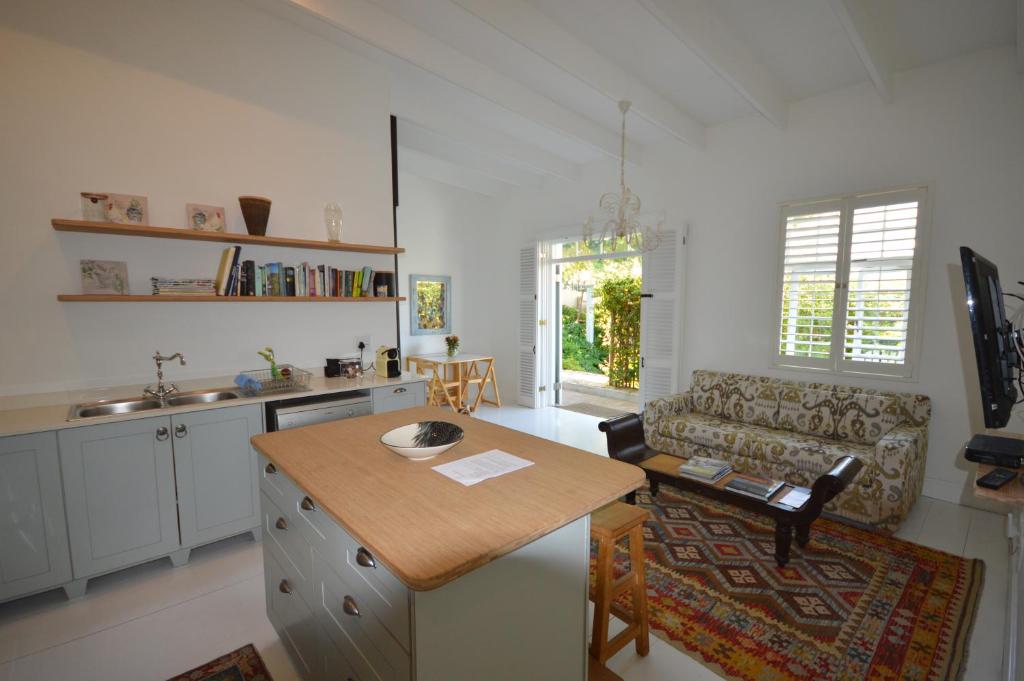 Willow Cottage في كيب تاون: مطبخ وغرفة معيشة مع طاولة وأريكة