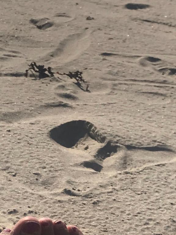 a persons foot in the sand on the beach at Village Way Apartments in Kincasslagh
