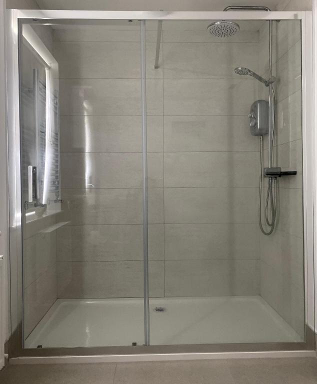 a shower with a glass door in a bathroom at Village Way Apartments in Kincasslagh