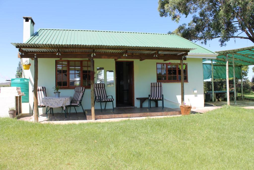 a small house with chairs and a table in a yard at Cicada Self Catering Cottage in Underberg