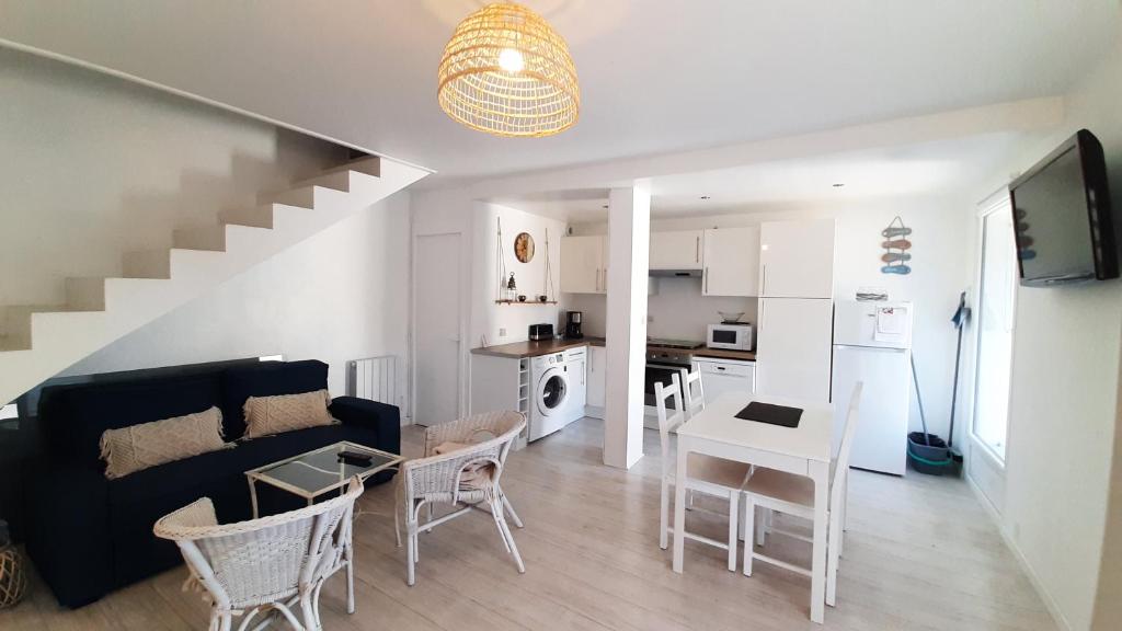 een woonkamer en een keuken met een bank en een tafel bij Maison Cormoran in Saint-Hilaire-de-Riez