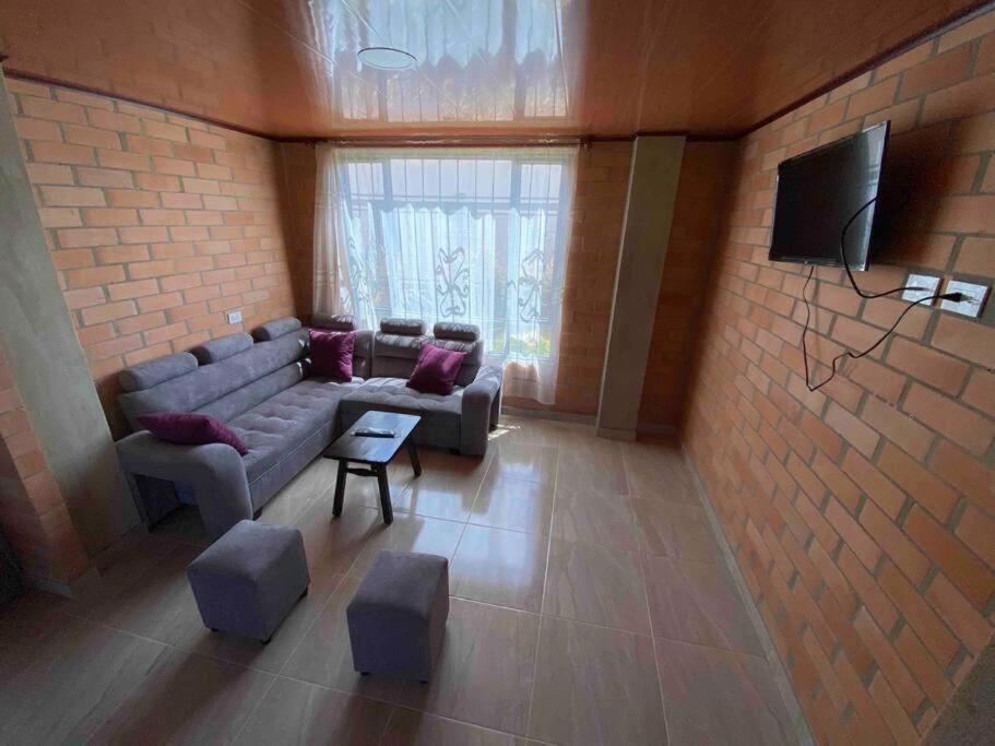 ein Wohnzimmer mit einem Sofa und einem TV in der Unterkunft Hotel Villa Stella "Apartamentos y habitaciones" in Paipa