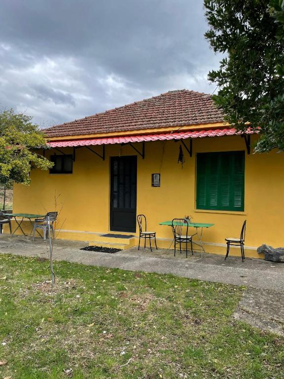a yellow house with a table and chairs in front of it at Villa Lochia - Καλημέρι in Elafopídima