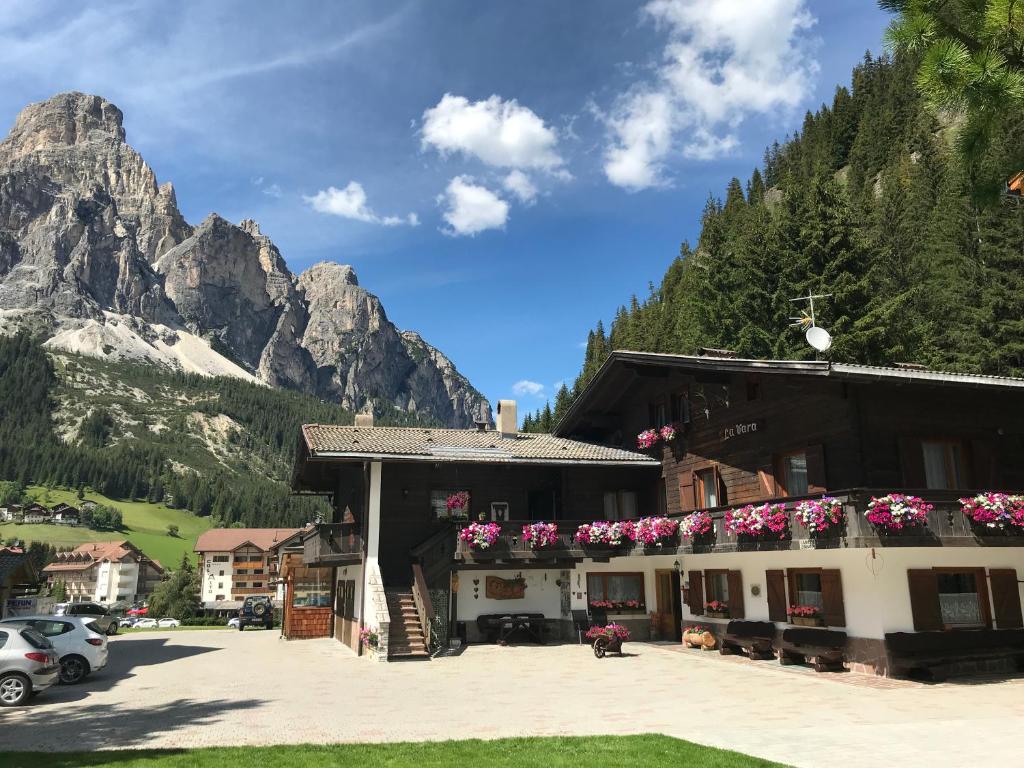 a building in the mountains with flowers on it at Apartments La Vara in Corvara in Badia