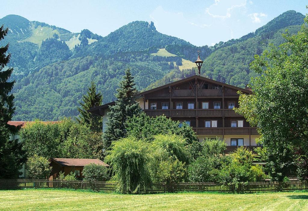 a building with a fence in front of a mountain at Hotel-Gasthof Sperrer in Grassau