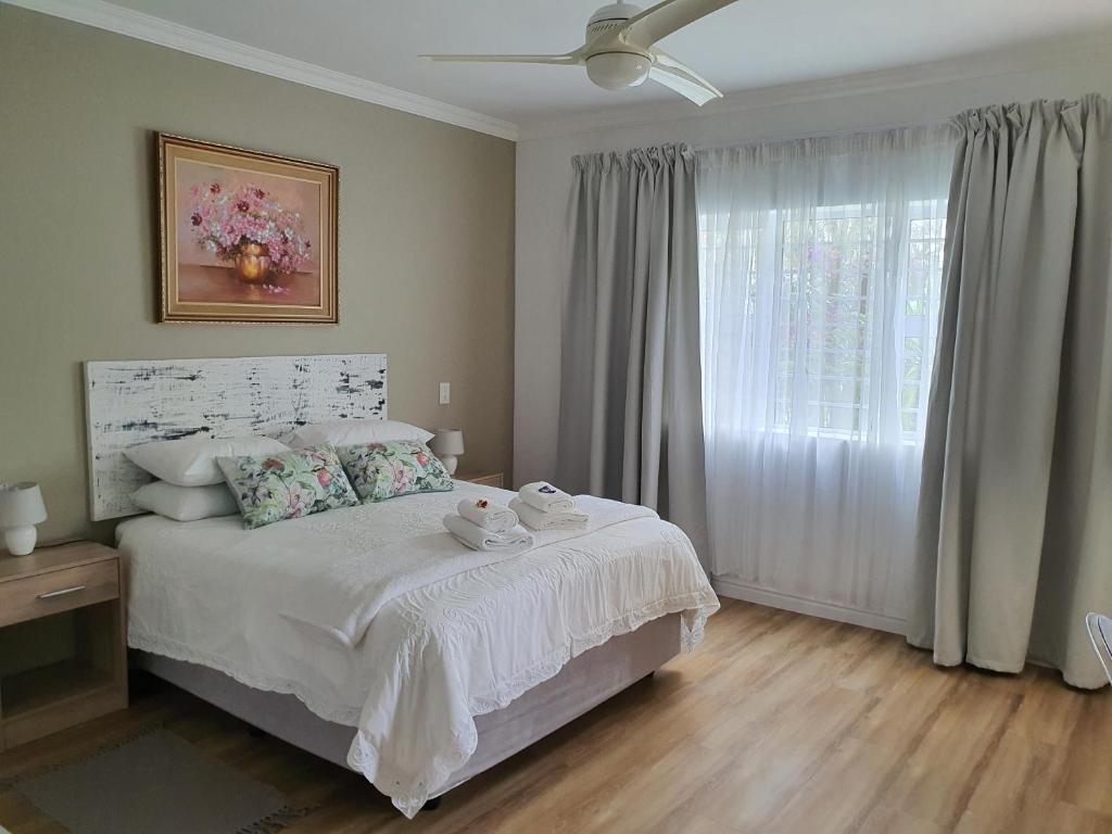 a bedroom with a bed with white sheets and a window at Plett57 - Self Catering - Room No2 in Plettenberg Bay