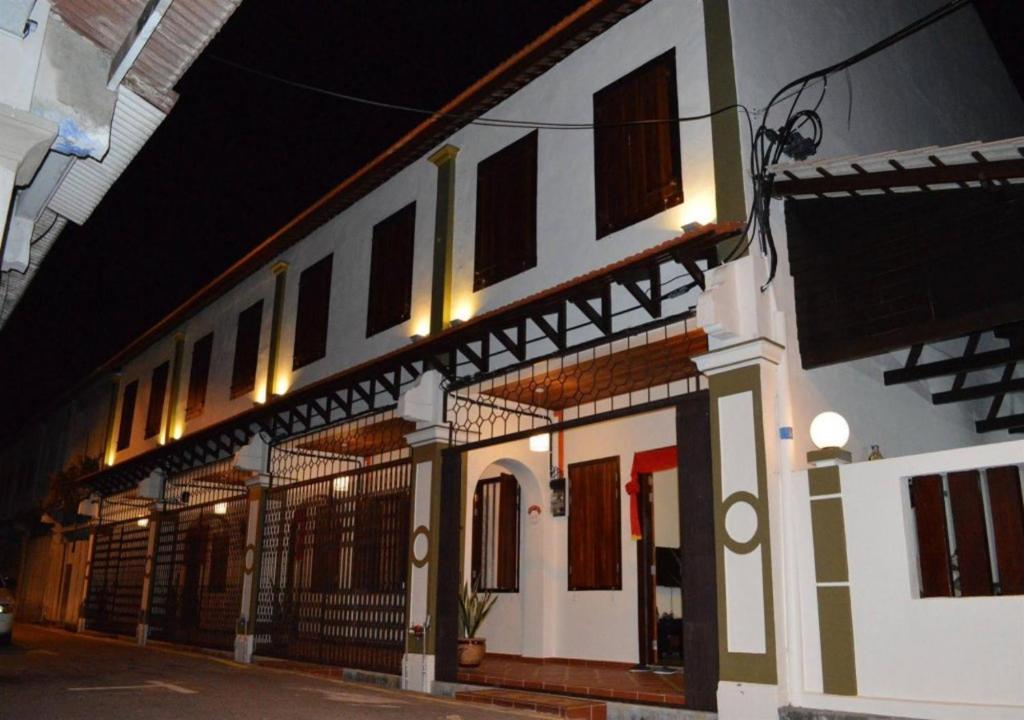 un edificio blanco con ventanas en una calle por la noche en Jawa Townstay en Melaka