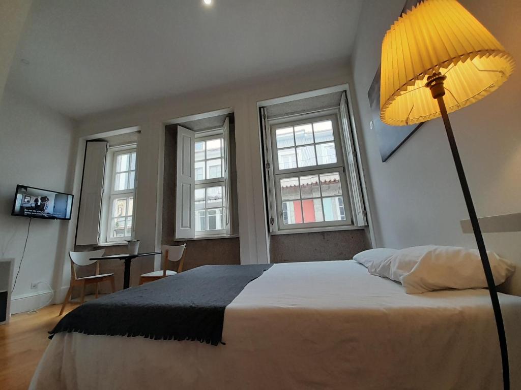 een slaapkamer met een bed met een lamp en een bureau bij Great&Cosy São Bento in Porto