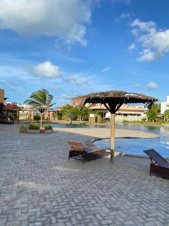 un patio avec des bancs et un parasol à côté d'une piscine dans l'établissement Santo Mar São Miguel do Gostoso, à São Miguel do Gostoso