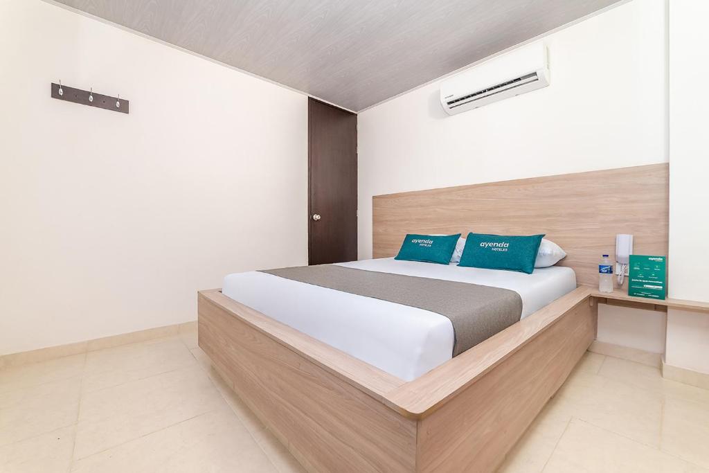 Ayenda Hospedaje WIV في كوكوتا: غرفة نوم مع سرير أبيض كبير مع وسائد زرقاء