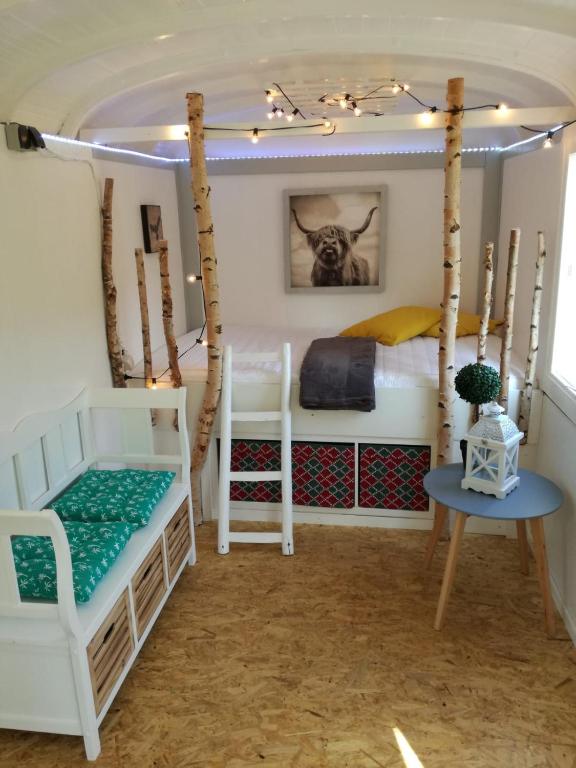 a room with two bunk beds and a table at Zurück zur Natur - Urlaub im Zirkuswagen, Sommeratelier oder Schindelwagen in Adenbach