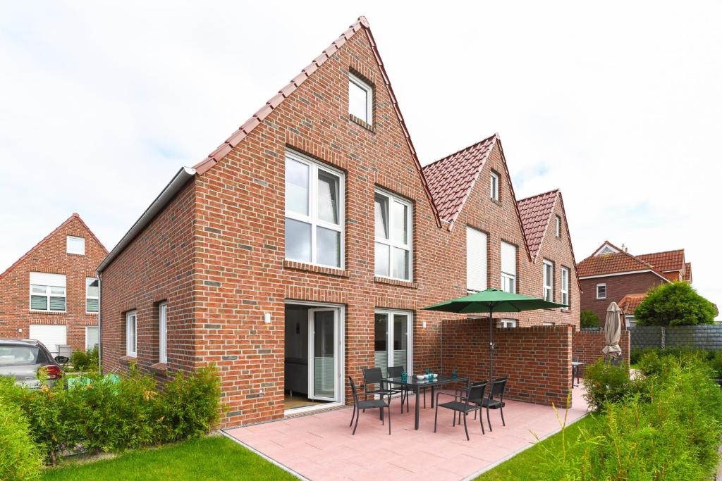 a brick house with a patio with a table and chairs at Ferienhaus Licht in Dornumersiel