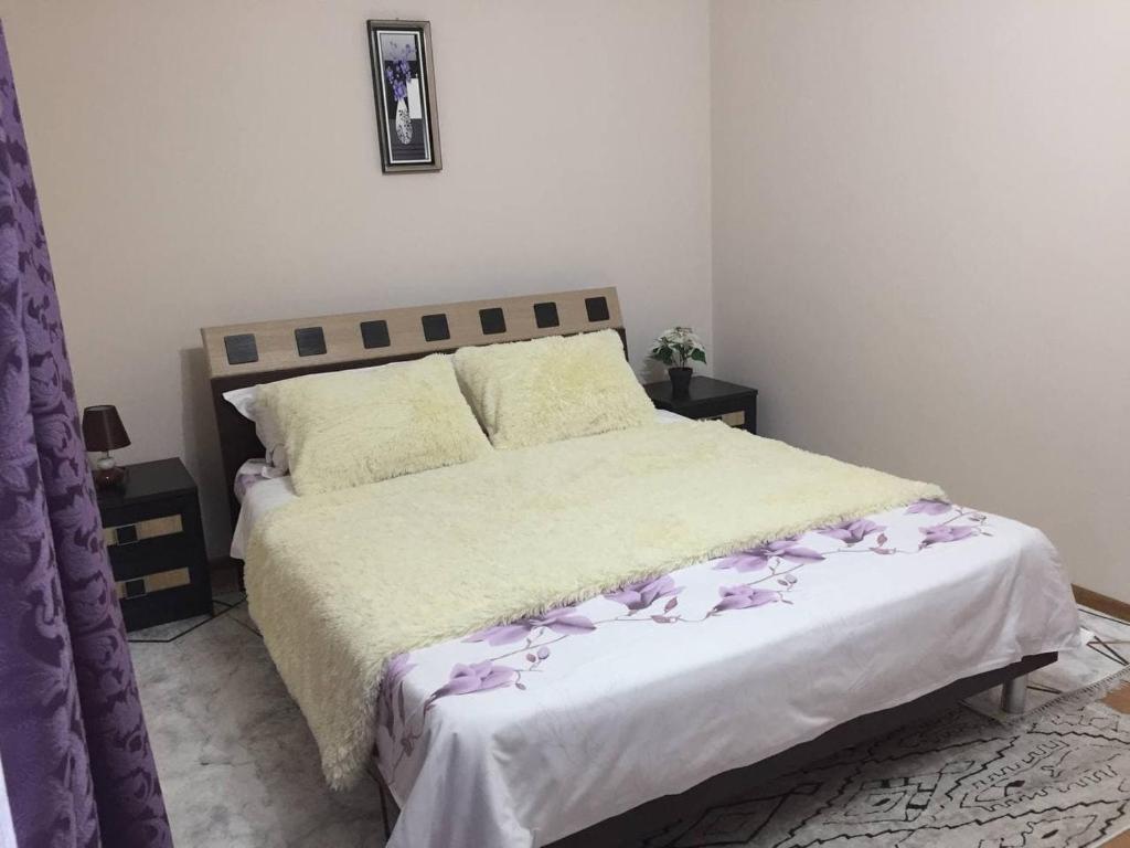 Un dormitorio con una cama grande con flores púrpuras. en Apartament simplu si confortabil, en Chişinău