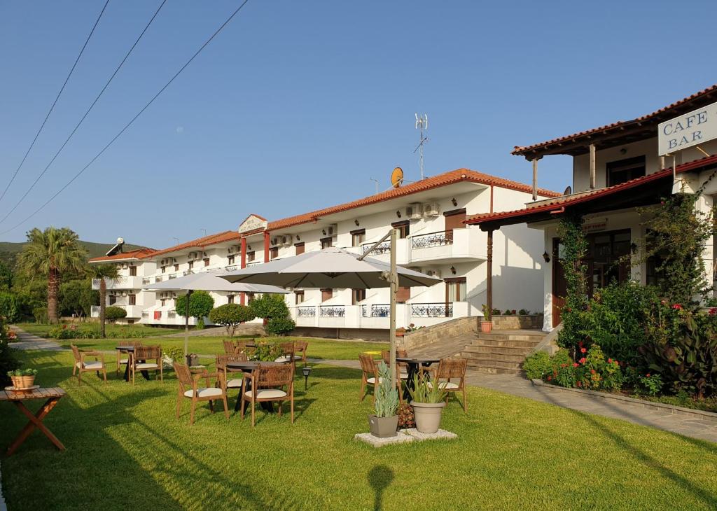 a hotel with tables and chairs in a yard at Hotel Ermioni in Kalamitsi