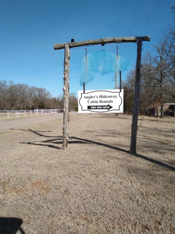 a sign on a pole in the middle of a field at Anglers Hideaway Cabins Extended Stay in Mead