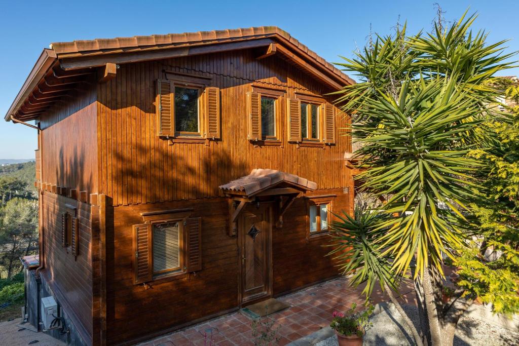 a wooden house with a palm tree in front of it at Casa de Madera en Calafell in Calafell
