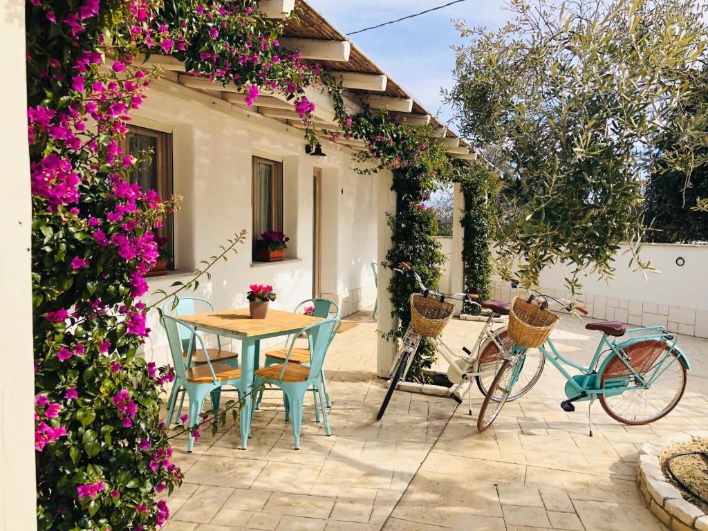 a patio with a table and chairs and flowers at Domus Deiana Case Vacanza in San Giovanni Suergiu