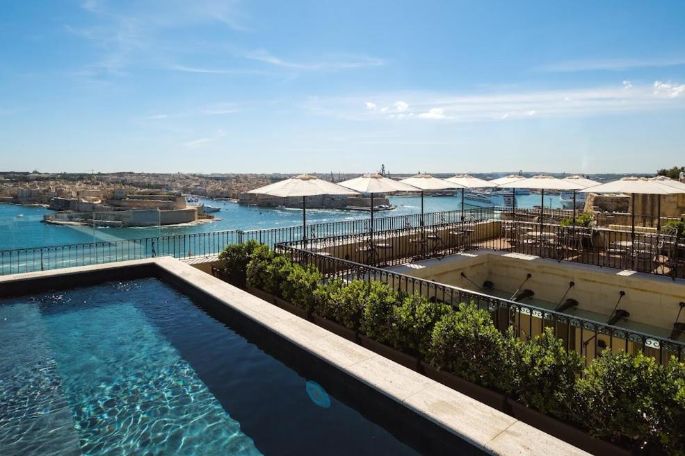 a swimming pool with umbrellas and the water at The Gomerino Hotel in Valletta