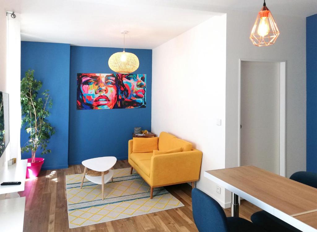 un salon avec une chaise jaune et un mur bleu dans l'établissement Appartement de charme centre ville, à La Ciotat