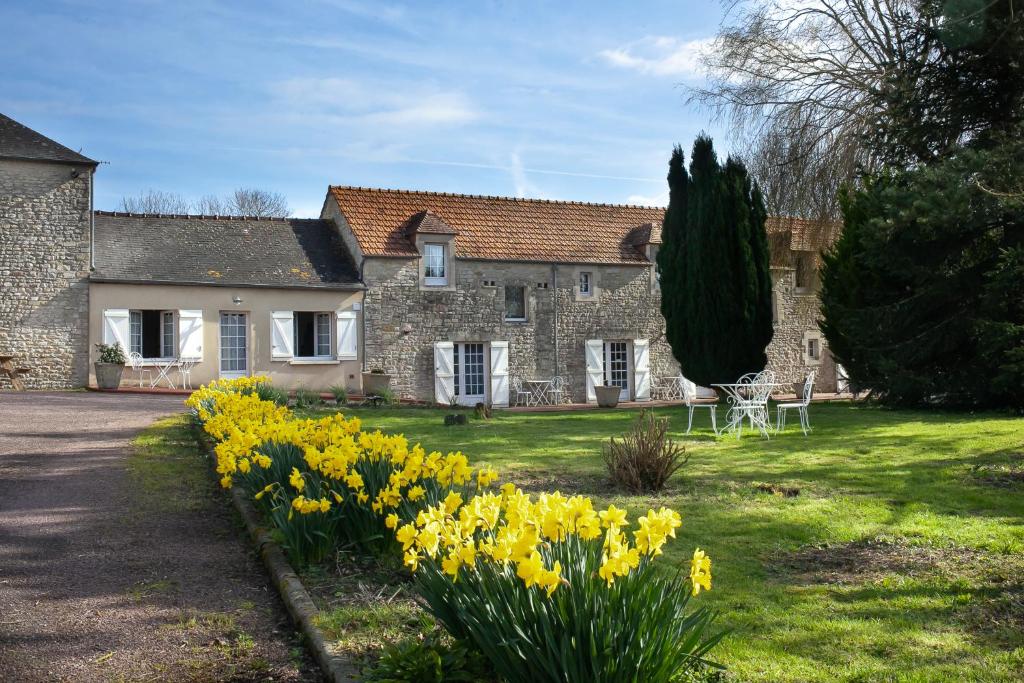 Uma casa com narcisos amarelos à frente. em Ferme des Goupillières em Maisons