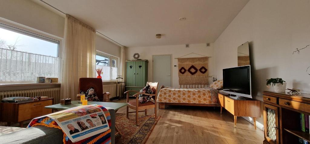uma sala de estar com um sofá e uma televisão em B&B Ut Kantuurke em Neer