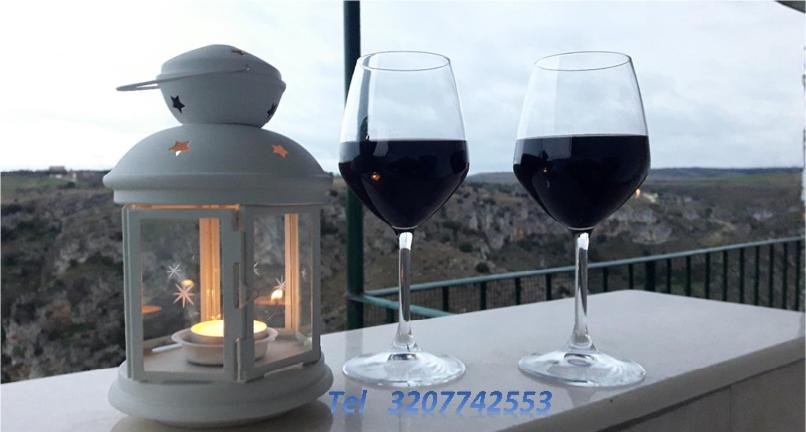 twee glazen rode wijn op een tafel met een lantaarn bij Vista Incantata - casa Bardaro in Matera