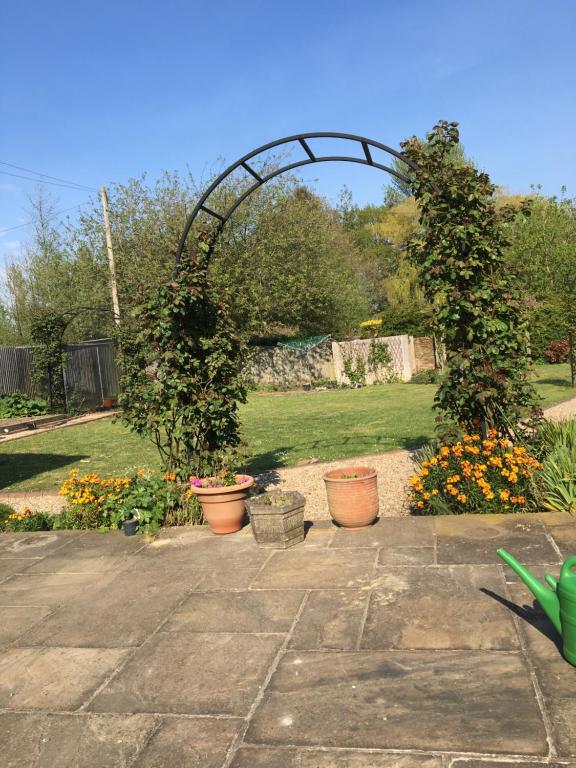 a garden with two potted plants and an arch at Little Orchard Cottage in Canterbury