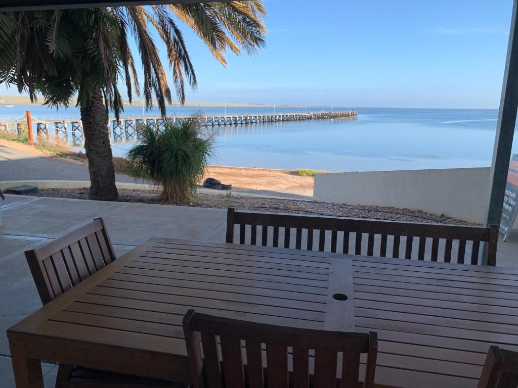 a wooden table and chairs with a view of the ocean at Beachside & Jetty View Apartment 6 - Captain's Apt in Streaky Bay