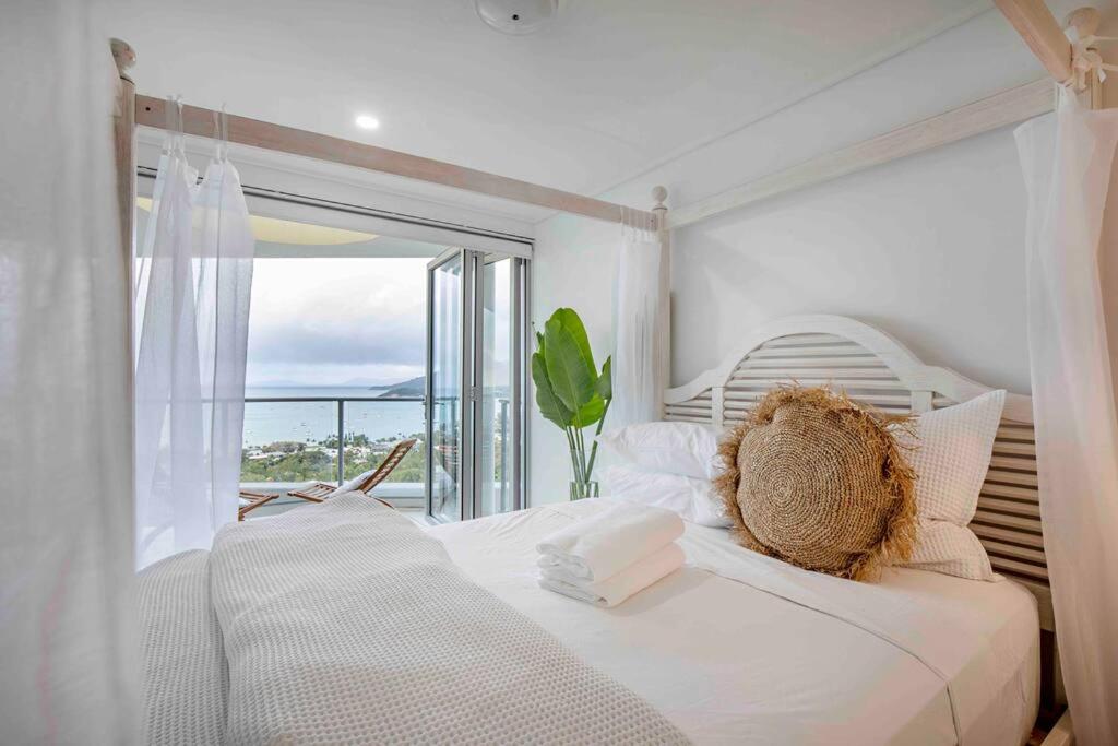 un dormitorio blanco con un osito de peluche sentado en una cama en The Top Floor Luxury accomodation for 2 Spa Bath, en Airlie Beach