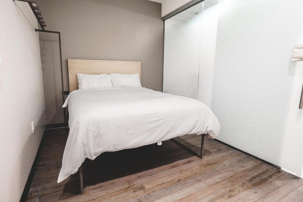 a small bedroom with a bed with white sheets at SOVA Micro-Room & Social Hotel in Dallas