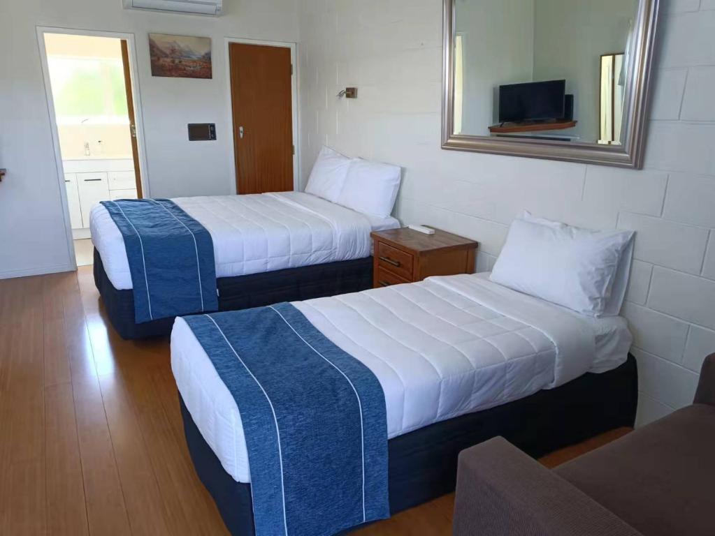 a hotel room with two beds and a mirror at Astral Motel in Whanganui
