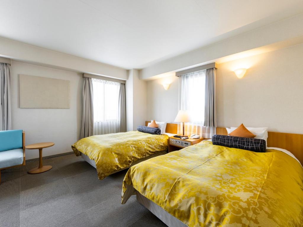 a hotel room with two beds and a couch at Hotel Dorf Shizuoka in Shizuoka