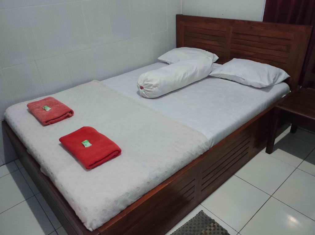 Una cama con dos toallas rojas encima. en Penginapan Mentorogo Kaliurang Mitra RedDoorz en Kaliurang