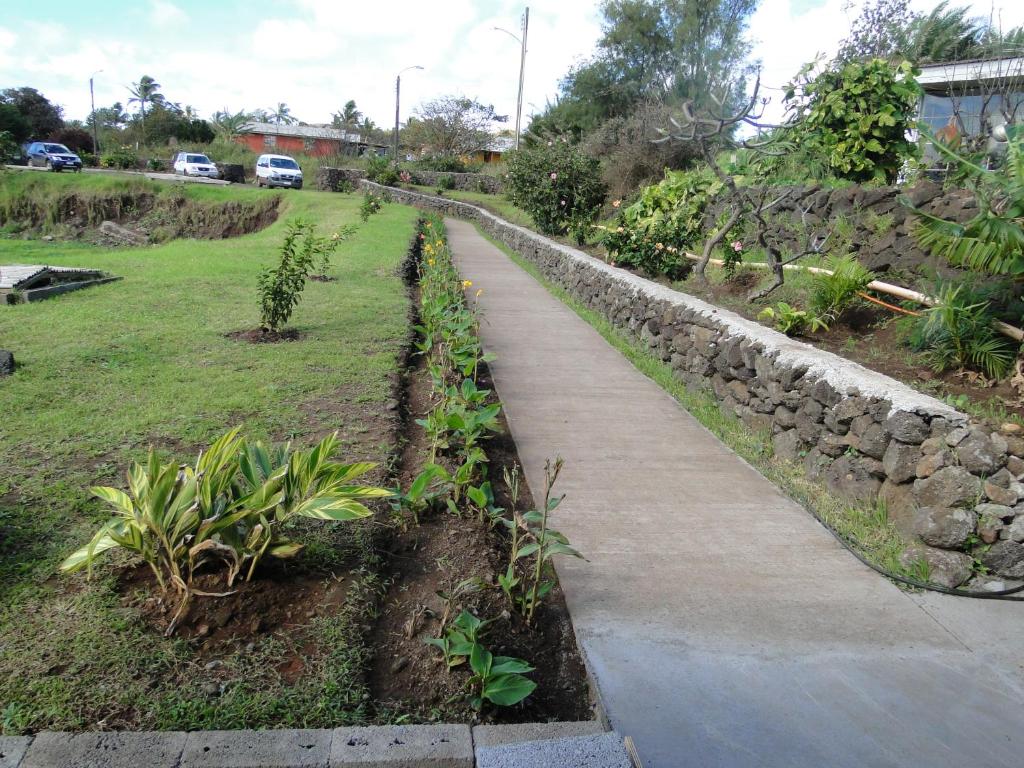 a walking path in a garden with a stone wall at Tupa Hotel in Hanga Roa