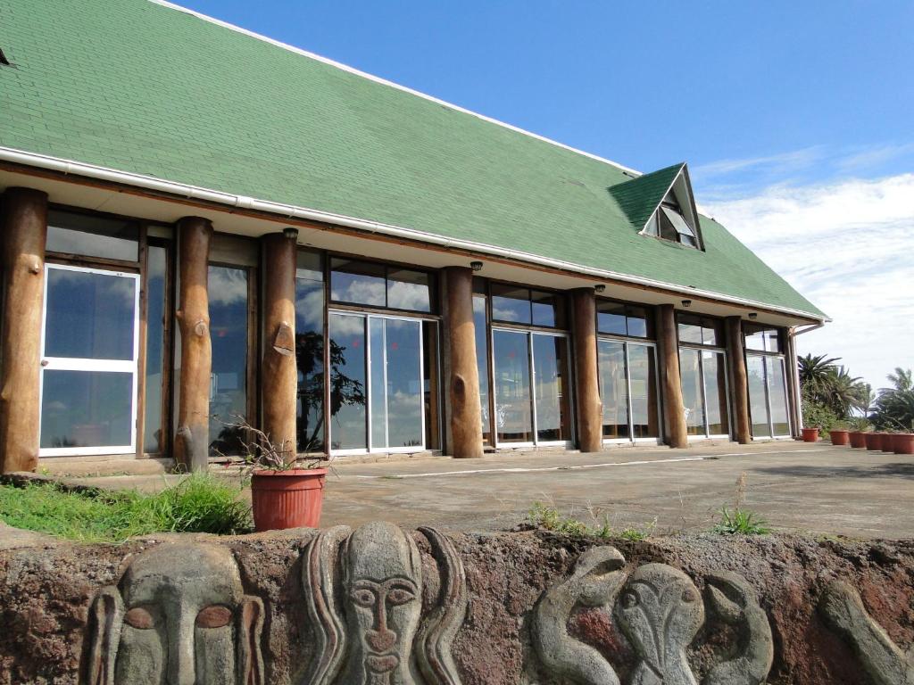 a building with a green roof and a building with windows at Tupa Hotel in Hanga Roa