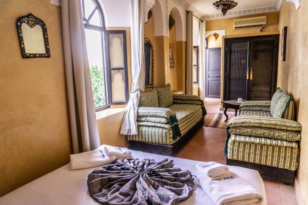 a room with a bed and two chairs and a window at Riad Amegrad in Marrakesh