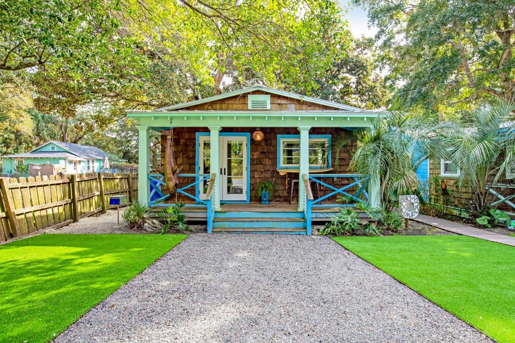 een klein blauw huis met een hek en gras bij This Place Cottage B in Folly Beach