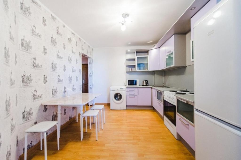 チタにあるDekabrist apartment at Babushkina 32bの白いキャビネット、テーブルと椅子付きのキッチンが備わります。