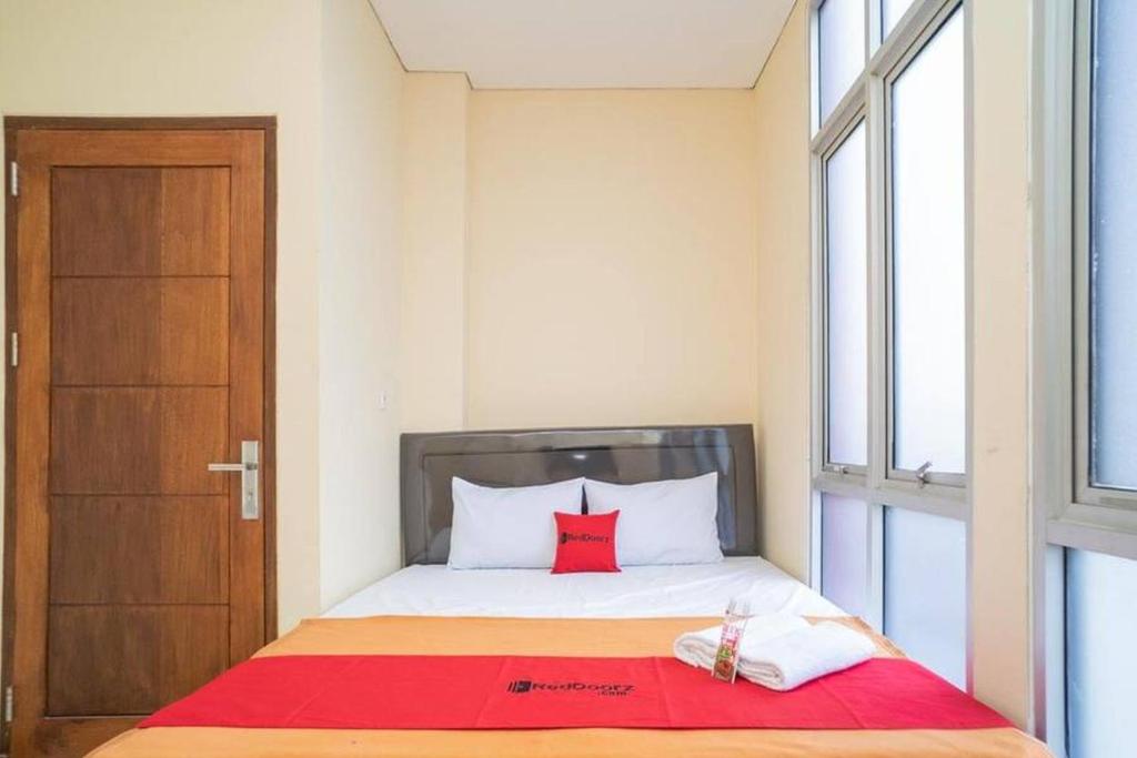 Kebandjahe的住宿－RedDoorz near Stasiun Tangerang，一间小卧室,配有一张带红色枕头的床