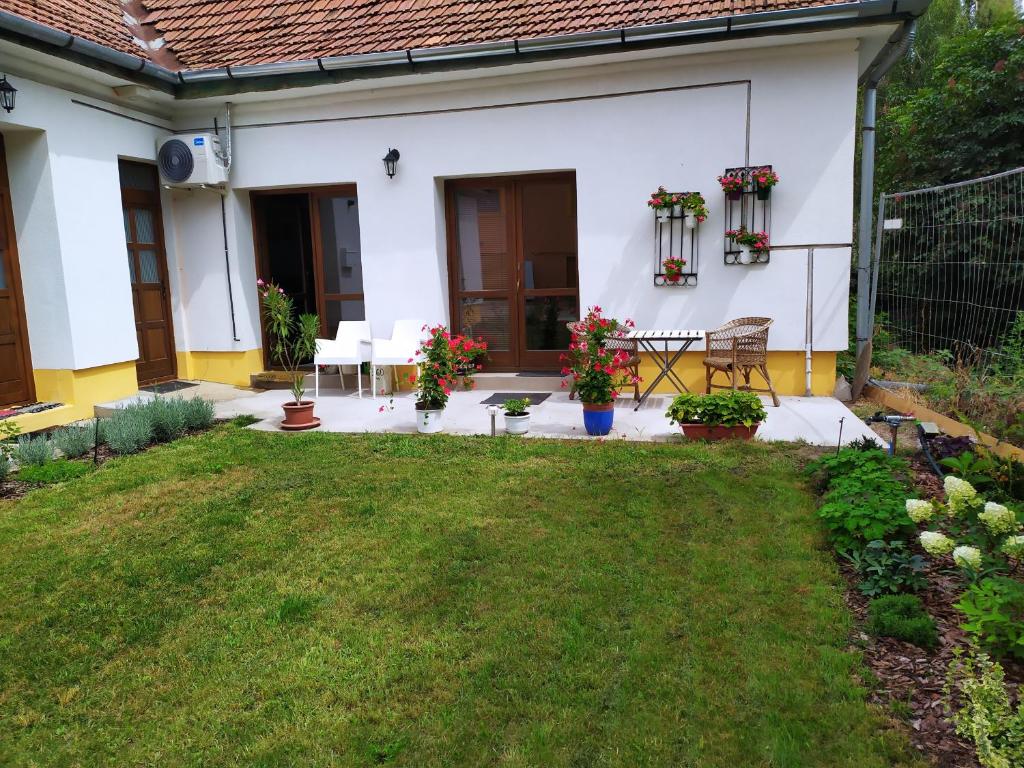 a backyard of a white house with a table and chairs at Napraforgó apartman Tokaj in Tokaj