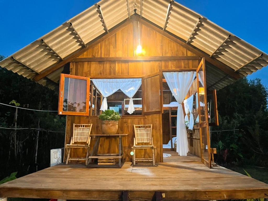 a large wooden cabin with chairs on a wooden deck at Bungalow - Farmstay Hoa Rừng U Minh in Cà Mau